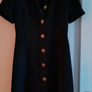 En fin svart klänning  - Svart klänning med guld knappar. Bra passform.