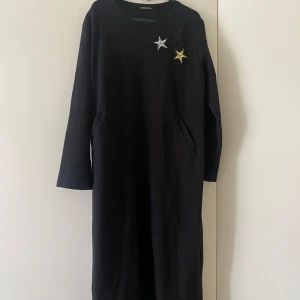 En vardags långklänning  - En svart vardagsklänning som både går att använda med bälte och utan. Stjärndetaljerad och har två små fickor. 