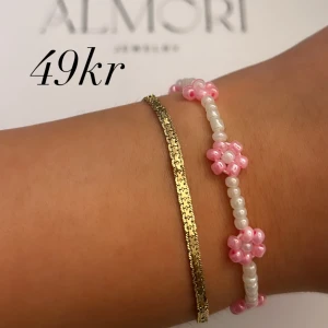 Två armband från Almori - Ett armband från Almori. Handgjort pärlarmband med vita och rosa pärlor formade som blommor.