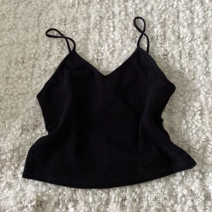 Svart linnetopp från Monki - En svart linnetopp från Monki i storlek M. Toppen har smala axelband och är tillverkad av 97% bomull och 3% elastan, vilket gör den bekväm och stretchig.