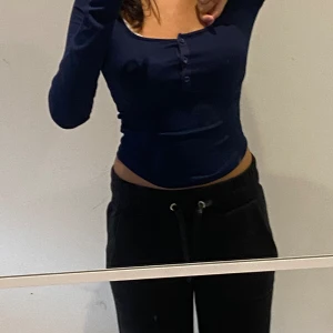 Mörkblå långärmad topp - En mörkblå långärmad topp med knappar framtill. Toppen är tight och har en rund halsringning.