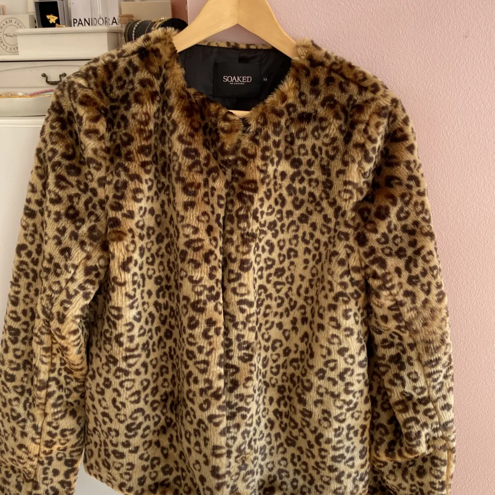 En leopardmönstrad pälsjacka från Soaked in Luxury. Jackan har långa ärmar och är tillverkad i ett mjukt och bekvämt material (polyester). Den har en normal passform och är perfekt för höst- och vintern.🍁🐆den går att knäppa hela vägen ner med väl gömda knappar🩷. Jackor.