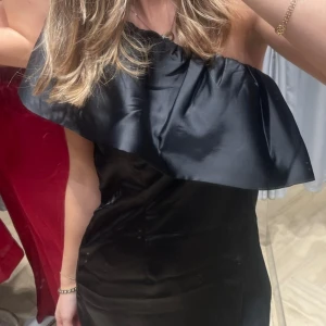 Svart klänning - En elegant svart klänning med en offshoulder på ena ärmen, 