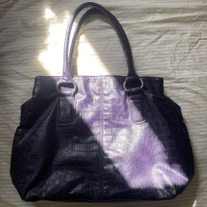 Handväska  - Stor och rymlig mörklila handväska. Köpt second hand, lite skavd i botten annars bra skick! Skriv vid frågor. Köparen står för frakt. 