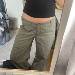 Khaki gröna vida byxor - Gröna Khaki parachute pants / cargo / vida byxor från Isabell Kristensen. I bra skick, storlek 34 :) Dragkedja och knutdetalj på benen. 