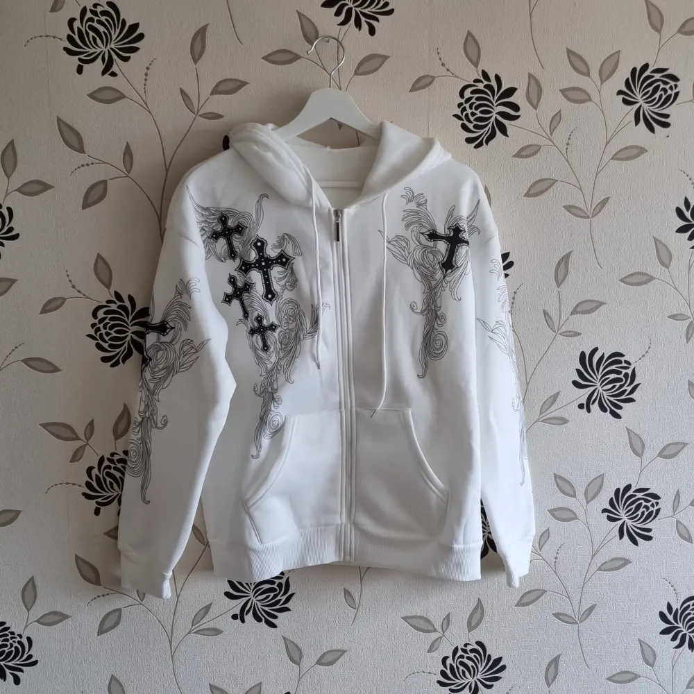Vit hoodie med zip i Y2K-stil, den har tryck med kors och en dragkedja med fickor i fram. Nyskick!. Hoodies.