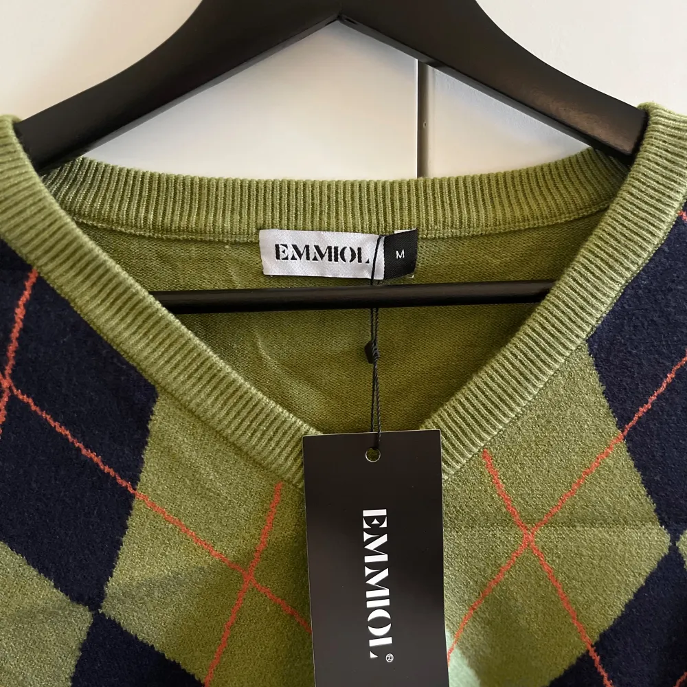 En olivgrön stickad tröja med argyle mönster från Emmiol. Storleken är M . Neuleet.