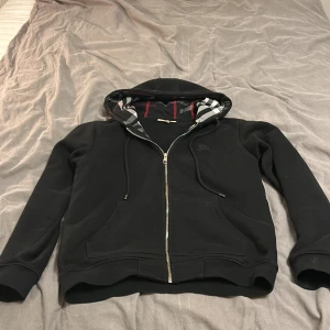 Svart burberry zip hoodie - Säljer min Burberry zip hoodie eftersom jag har växt ur den och det inte riktigt är min stil. Skick 8/10 (Pris går att diskutera) Byte fungerar