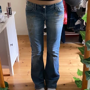 Jeans med guldbrodyr - Supersnygga lågmidjade jeans köpta på humana med gulddetaljer💫lite utsvängda där nere och har en ljusblå wash. Bra skick men lite slitna vid hälarna..! 82cm innerbenslängd, 43cm midja tvärsöver🤙