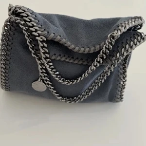 Stella McCartney väska - Säljer min Stella McCartney väska, modellen falabella tiny som är i nyskick! (Därav priset) självklart äkta, se sista bilden. Väskan är köpt på NK i vintras för 9200kr Färgen är grå/blå. 