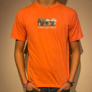 Somrig t-shirt  - Charmig orange t-shirt med tryck på bröstet. Tröjan är i gott skick och är köpt på lindex. Materialet är även stretchigt. Skriv vid fler frågor.