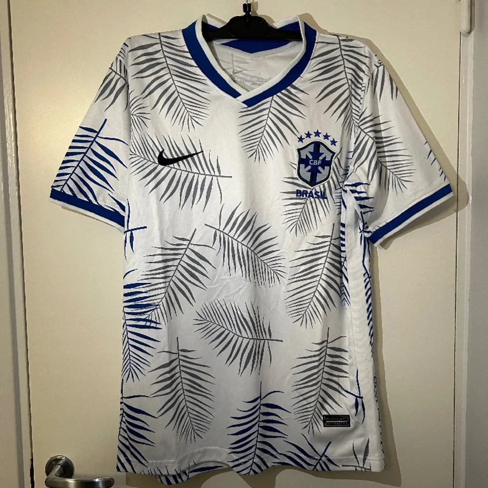 Vit Brasilien fotbollströja med grå/blåa detaljer. Storlek S men upplevs lite större så passar även storlek M. Helt ny och oanvänd med etikett på.. T-shirts.