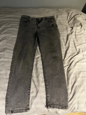 Tommy Hilfiger jeans - Säljer ett par grå jeans från Tommy Hilfiger med klassisk femficksdesign och raka ben. Jeansen har en snygg tvättad look och är tillverkade i slitstarkt denim. Passar dig som gillar stilrena och tidlösa plagg med en modern touch. Size 34