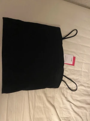 Svart spaghetti-linnetopp Gina Tricot XS - Säljer en svart spaghetti-linnetopp från Gina Tricot, kollektionen Elevated Basics. Toppen har tunna axelband och är i en enkel, stilren design. Perfekt att matcha med jeans eller kjol. Storlek XS. Aldrig använd. Köpte för 99kr men säljer nu för 50kr 