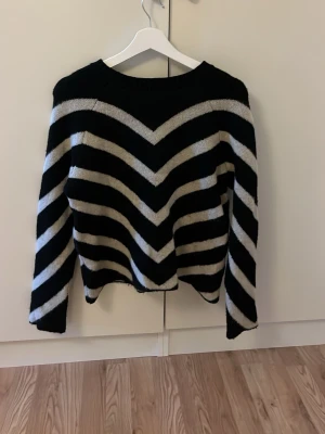 Svart och vit randig stickad tröja ONLY - Säljer en stickad tröja från ONLY i storlek S. Tröjan har svarta och vita breda ränder i ett snyggt V-mönster, rund hals och långa ärmar. Perfekt för dig som gillar en chill och trendig look med lite edge.