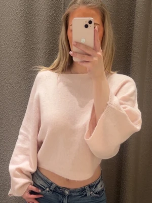 Ljusrosa croppad stickad tröja - Superfin ljusrosa stickad tröja med croppad passform och vida ärmar. Perfekt att matcha med jeans för en avslappnad och trendig look. Mjuk och skön, passar bra till både vår och höst.