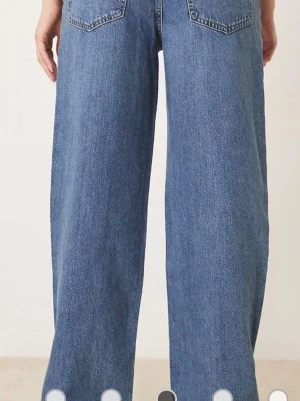 Blå wide jeans med dragkedja - Säljer ett par blå jeans med breda ben och klassisk femficksdesign. Jeansen har dragkedja och knapp framtill samt bälteshällor. Materialet är robust denim i bomull och passformen är loose med en modern wide siluett.