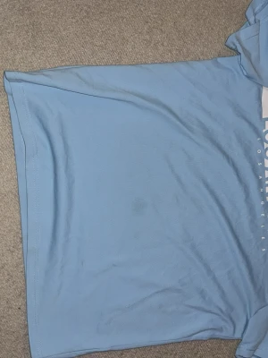 Ljusblå t-shirt från manfinity - Säljer en ljusblå t-shirt från Manfinity i storlek S. T-shirten har klassisk rund hals och korta ärmar. Materialet är mjukt och känns som bomull, perfekt för chill dagar. Diskret tryck på framsidan med textdetaljer. Enkel och clean design.