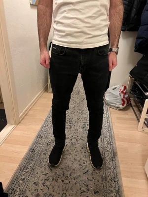 Mörkgråa Prada jeans - Säljer ett par mörkgråa jeans från Prada med klassisk femficksdesign och diskret Prada-logga på fickan. Jeansen har en tight passform och är tillverkade i stretchigt jeansmaterial för extra komfort. Perfekta till sneakers och t-shirt.