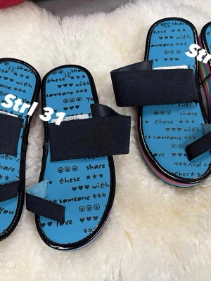 Färgglada sandaler med text, strl 31 / 32 - Säljer ett par sandaler med blå innersula och svart text med hjärtan och stjärnor. Remmarna är svarta och elastiska, och sulan har färgglada ränder i rosa, blått, grönt och gult. Platt sula och öppen tå, perfekt för dig som gillar lekfull stil, 2 par sandaler for 300kr 