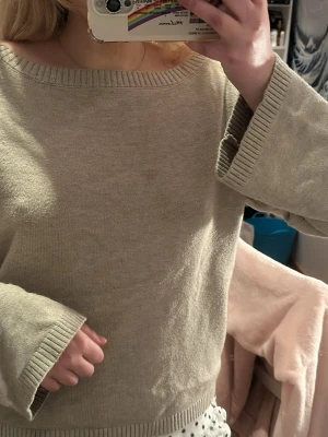 Beige stickad offshoulder-tröja - Säljer en beige stickad tröja med bred ribbad kant i halsringningen och vid ärmsluten. Tröjan har en avslappnad passform och kan bäras offshoulder för en chill vibe. Perfekt till både jeans och kjol. Från Ginatricot