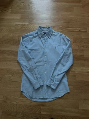 Ralph Lauren skjorta - Ljusblå Ralph Lauren skjorta i extremt bra skick inga defekter 10/10🙌🏽, Storlek S, Axelmått ≈ 43cm Längd ≈ 70cm. Skriv gärna vid fler funderingar.