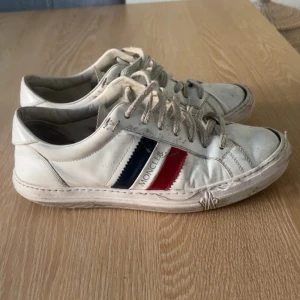 Vita Moncler sneakers med röd och blå detalj - Hej, jag säljer dessa snygga skor för de har blivit för små. Nypris 4500-4000 hör av er vid minsta lilla