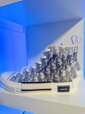 Dior b23-Oblique Sneakers high top storlek(40,5) - Detta är ett par Dior b23-Oblique sneakers köpta direkt från Dior.com (2020/8-14) se kvitto.  Storlek (40,5) EU  Sko-kartong, ett par extra oanvända skosnören och diorpåse ingår.  Skorna är använda ytterst lite och ser nästan helt nya ut, priset som är satt nu beror på att de har alla tillbehör till, de är extremt bra skick och hög efterfrågan dessutom har b23 serien gått upp mer i pris.