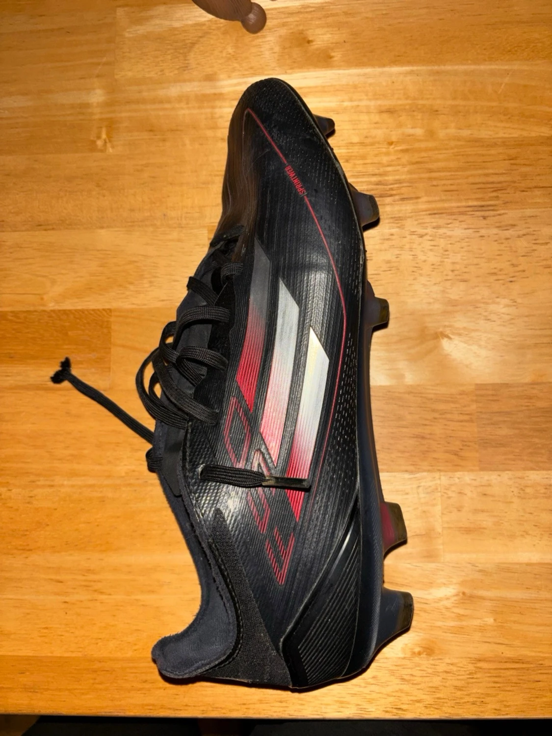 Svarta Adidas fotbollsskor med röd detalj