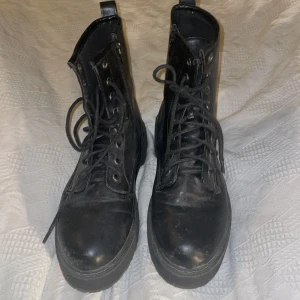Svarta boots från New Yorker, storlek 39 - Säljer ett par svarta boots från New Yorker i storlek 39. Skorna har snörning, dragkedja på sidan och en rejäl plattformssula. Tillverkade i skinnimitation med rund tå och högt skaft, perfekta för dig som gillar chunky stil.Nypris 400kr.