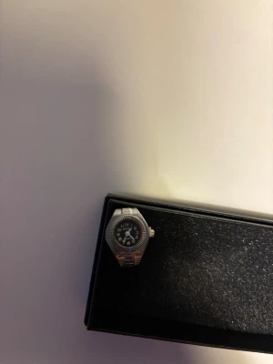 Silvrig guldring med svart urtavla - En silverfärgad ring med inbyggd klocka. Passar till alla tillfällen, stilren och oanvänd. Justerbar storlek.