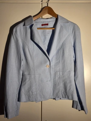 Vintage ljusblå kavaj från Tessie - Snygg ljusblå kavaj från Tessie i 100% bomull. Klassisk modell med krage, en knapp framtill och två stora fickor. Perfekt att slänga på över en t-shirt för en chill och fräsch look. Passar dig som gillar stilrena och enkla plagg.