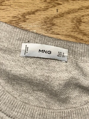 Beige stickad tröja från MNG - Beige stickad tröja från MNG med rund halsringning och ribbade muddar vid ärmslut och nederkant. Enkel och stilren design 