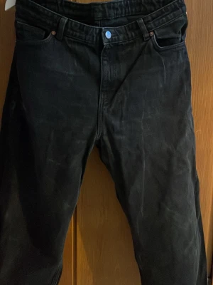 Svarta Levi's 501 jeans straight fit - Klassiska svarta Levi's 501 jeans med rak passform och fem fickor. Jeansen har knappgylf och är tillverkade i slitstarkt bomullsjeans. Perfekta för dig som gillar tidlös stil och enkel design.