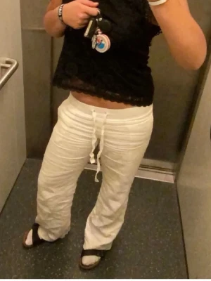 Alohaba Linnebyxor  - Säljer ett par vita linnebyxor med avslappnad passform och snörning i midjan. Byxorna har raka ben och är perfekta för sommarens alla dagar. 