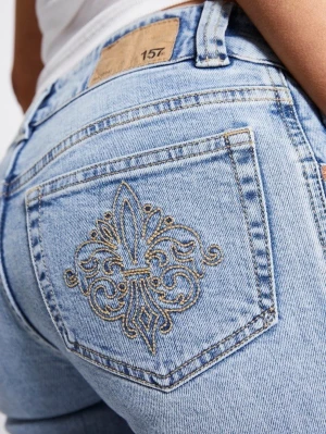 Bootcut ljusblå jeans med broderi - Snygga ljusblå bootcut jeans med unikt broderat mönster på bakfickan. Jeansen har klassisk femficksdesign, normal passform och är tillverkade i mjukt bomullsjeansmaterial. Perfekta för dig som vill sticka ut lite extra med detaljer.
