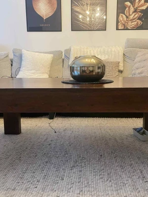 Rektangulärt soffbord i mörkt trä - Stilrent soffbord i massivt mörkbrunt trä med rektangulär form och robusta ben. Bordet har en enkel design utan synliga märken eller logotyper och passar perfekt som mittpunkt i vardagsrummet. Bordsskivan är slät och benen är fyrkantiga för en stabil känsla. Därmed en vacker tv bänk till som passar perfekt tillsammans. 1000kr st 1500kr för båda 