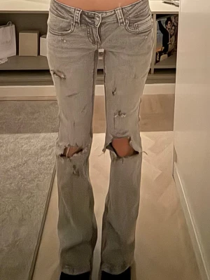 Snygga grå bootcut jeans med hemmagjorda hål - Grå bootcut jeans ifrån Gina tricot med hemmagjorda hål och slitningar.