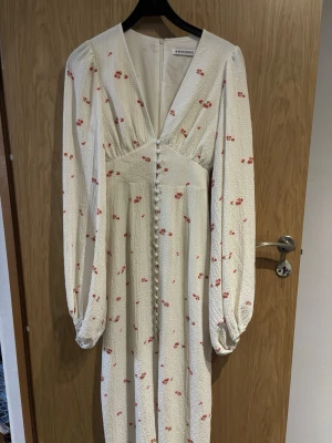 Vit långklänning med blommor från Adoore - Trendig klänning från Adoore i strl 34. Använd en gång! Säljs pga kommer inte till användning 1300kr