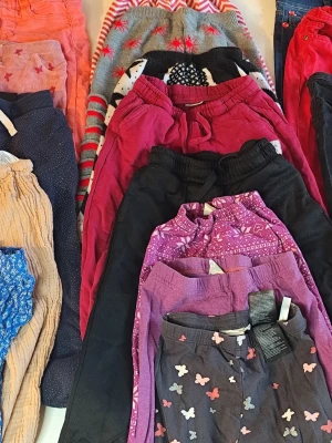 Färgglada byxor i olika material storlek 110/116 - Säljer ett mixat paket med byxor 18plagg i flera färger och mönster, bland annat lila, rosa, svart och beige. Några har fjärilar, hjärtan eller stjärnor som mönster. Materialen varierar mellan bomull och syntet, vissa med snörning i midjan. Perfekt för dig som gillar variation i garderoben .Du är varmt välkommen att kika på mina andra annonser.