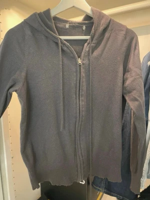 Mörkgrå/blå zip hoodie med huva - En enkel och stilren mörkgrå hoodie med dragkedja framtill och justerbar huva med snören. Hoodien har långa ärmar och ribbade muddar vid ärmslut och nederkant. Perfekt för en avslappnad look och passar till det mesta. Lite smutsig på ett ställe. Men det går nog ta bort.