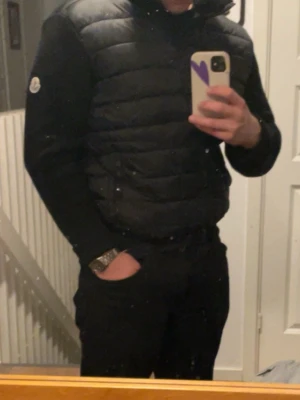 Svart pufferjacka från Moncler - Snygg svart cardigan från Moncler med quiltad front och ärmar i mjukare material. Jackan har hög krage och diskret Moncler-logga på ärmen. Perfekt för kyliga dagar och ger en stilren look. En riktig jovol nu under vinter men även under hösten och våren. Pris kan diskuteras vad snabb och smidig affär!