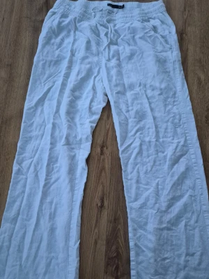 Vita linnebyxor med resårmidja från lager 157 - Säljer ett par vita linnebyxor med avslappnad passform och resår i midjan. Byxorna har raka ben och sidofickor, perfekta för varma dagar. Materialet är svalt linne och färgen är klassiskt vit.