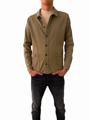 Overshirt - Snygg olivgrön overshirt med klassisk krage och knäppning framtill. Två stora fickor framtill och raka ärmar. Perfekt att slänga över en t-shirt för en avslappnad look. Tillverkad i bomull för skön känsla.