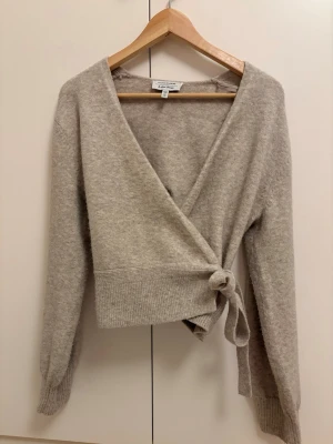 Beige omlottkofta från & Other Stories - Snygg beige omlottkofta från & Other Stories med knytband i midjan och ribbade muddar. Använd enstaka gånger så i mycket bra skick!💕