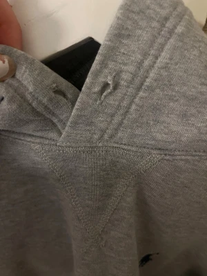 Grå sweatshirt från Polo Ralph Lauren - Klassisk grå sweatshirt från Polo Ralph Lauren med broderad marinblå logga på bröstet. Tröjan har rund halsringning och ribbade muddar. Perfekt för en avslappnad och stilren look. 