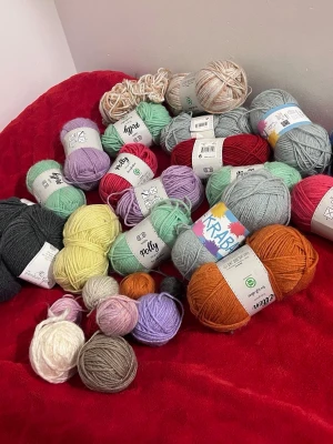 Stort garnpaket i blandade färger - Ett stort paket med garnnystan i olika färger som lila, mintgrön, röd, orange, gul, grå, vit och beige. Märken som Polly, Krabat och Panduro ingår. Perfekt för stickning eller virkning. Blandade material och tjocklekar. Pris kan diskuteras 