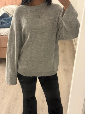 Ljusgrå oversized stickad tröja - Mysig ljusgrå stickad tröja med avslappnad passform och rund halsringning. Tröjan har långa ärmar och ribbade muddar vid ärmslut och nederkant. Perfekt för lager på lager och enkel att matcha med olika stilar. Passar för dig som brukar ha storlek S.