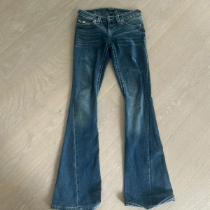 True Religion bootcut jeans blå - Säljer ett par blå jeans från True Religion med tydliga vita kontrastsömmar och broderade detaljer på bakfickorna. Det är i storlek 23 och är jätte snygga❣️
