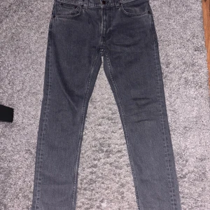 Grå Lean Dean jeans från Nudie Jeans - Säljer dessa par Nudie jeans i passformen Lean Dean och i färgen Grey Ash pga att de inte passar mig. De har en klassisk femficksdesign och snygga broderade bakfickor. De är endast använda ett fåtal gånger och har inge defekter. Hör av dig vid frågor! Pris kan diskuteras vid snabbaffär.